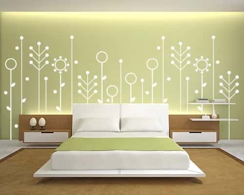 Slaapkamer met een groene wand waarop een wit bloemmotief is aangebracht